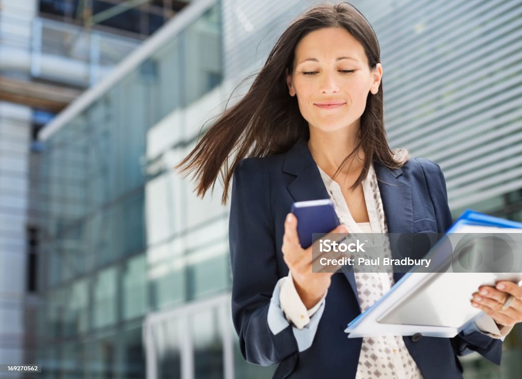 Businesswoman using cell phone in office  Using Phone Stock Photo