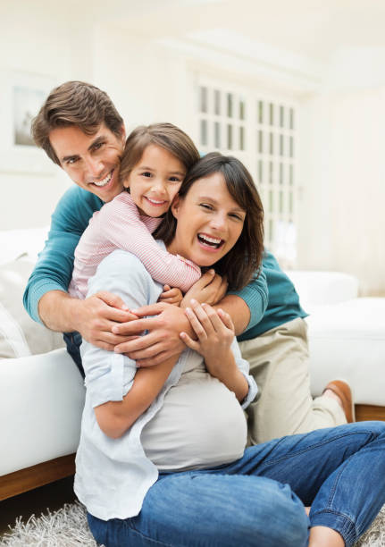 famiglia abbracciare nel salotto - floor two parent family couple home interior foto e immagini stock