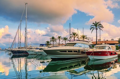 Stunning view of luxury yachts at the pier against the sunset. Yachts and boats anchored in marina.