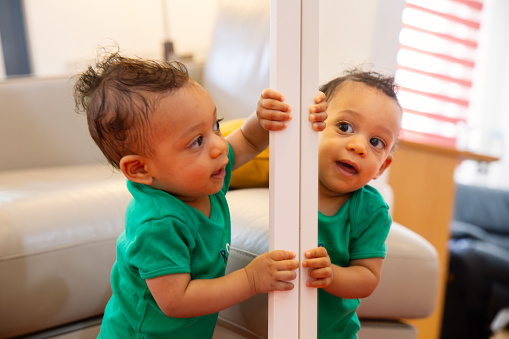 Baby enjoying looking at his reflection in the mirror.