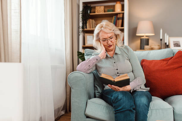istock Senior woman sitting at home and reading a book. 1692773567