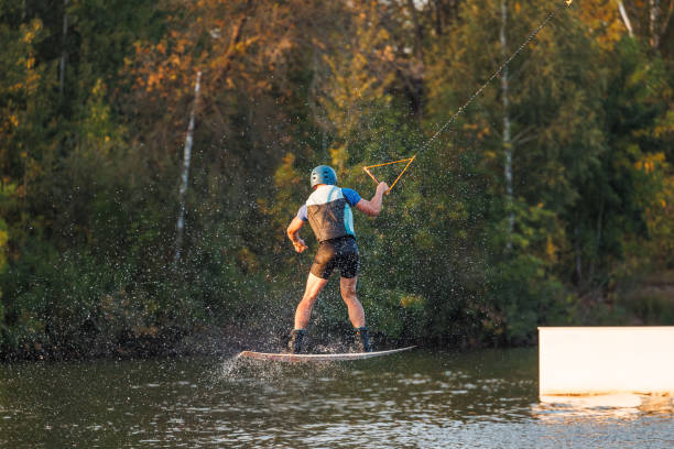 istock An athlete jumps from a springboard. Wakeboard park at sunset. A man performs a trick on a board 1692797301