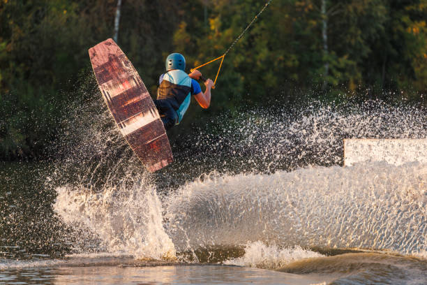 istock An athlete jumps from a springboard. Wakeboard park at sunset. A man performs a trick on a board 1692797303