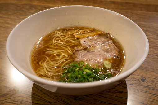 Japanese Shoyu soya sauce ramen noodles adorned with marinated bamboo shoots (menma), green onions, and sliced barbecued and braised pork (chashu).