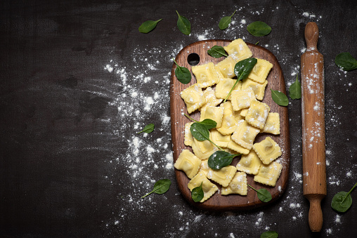 Homemade pasta with spinach leaves - Ravioli, in a large wooden bowl, on a wooden background. Traditional Italian food