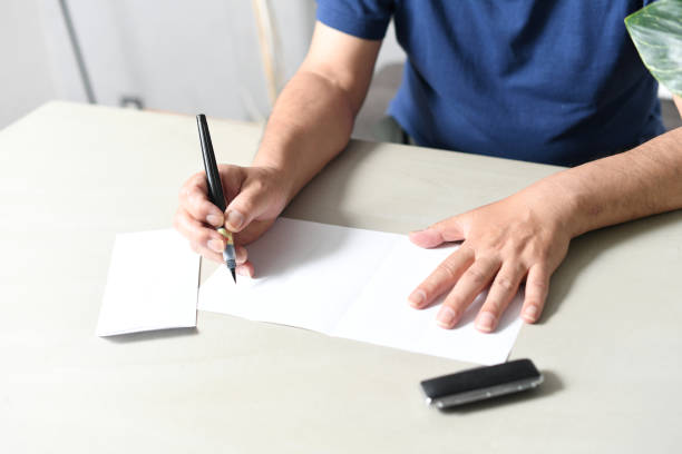 istock Hand of an elderly Asian man writing a sentence 1692867516