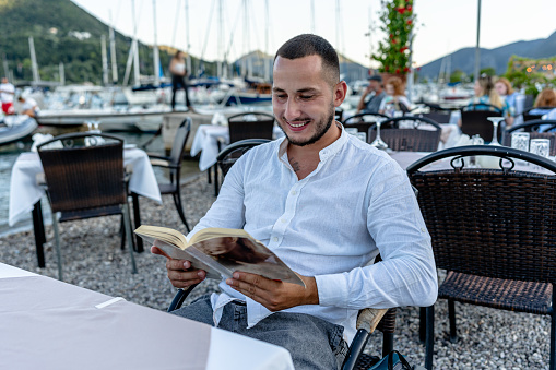 Surrounded by nature's charm in the taverna garden, the young man dives deep into the world of his chosen book