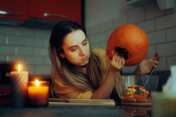 istock Funny Woman Scooping Seeds from a Pumpkin Decoration at Home 1692936191