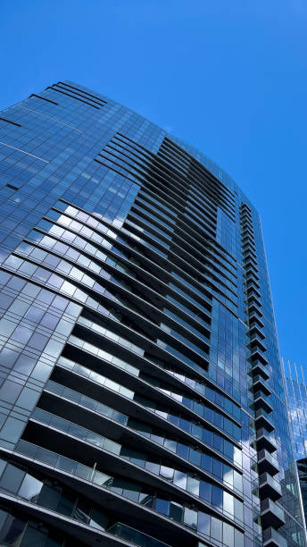 istock Angled view of a large, window covered building corner against a blue, cloud filled sky 1692946519