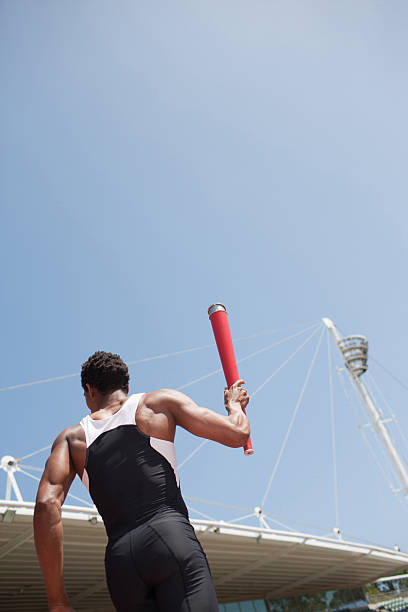 Runner running with torch on track  mens track stock pictures, royalty-free photos & images