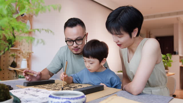 asian parents practice Chinese calligraphy with their children