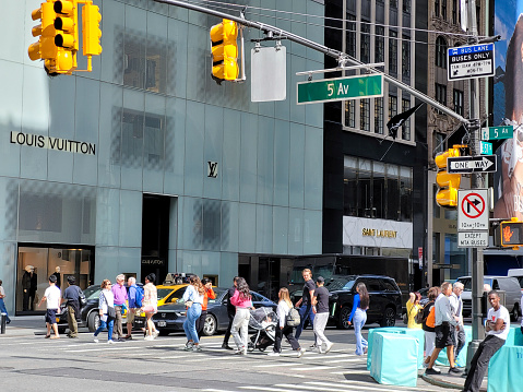 New York, New York, USA - September 15, 2023: People crossing at the corner of 57th Street and Fifth Avenue in Manhattan.
