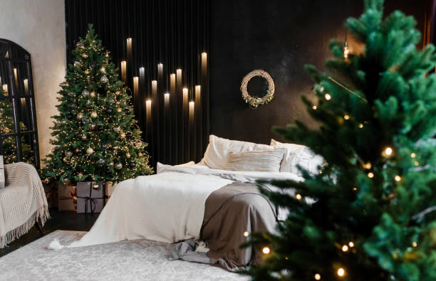 istock Bedroom interior decorated for Christmas holidays. Home interior with a Christmas tree on a dark wall background. 1693000757