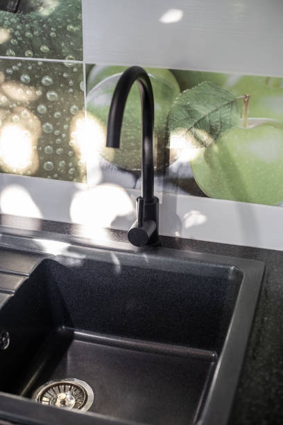 istock A black sink with a faucet on a black kitchen countertop and a light tile backsplash, illuminated by the rays of the sun 1693004003