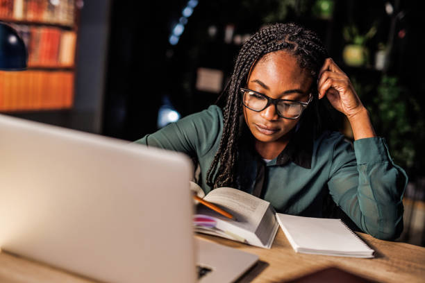 istock Tired female student taking notes and studying at her desk late at night 1693026890