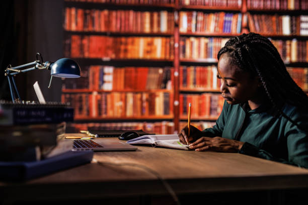 istock Young woman using laptop, writing notes and studying at the library 1693027164