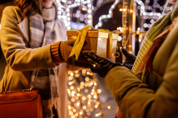 Caring young woman surprising her girlfriend with a Christmas gift box