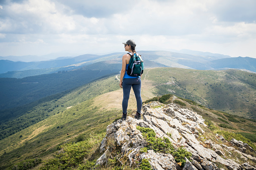 Young woman hiking in nature on a beautiful mountain range.