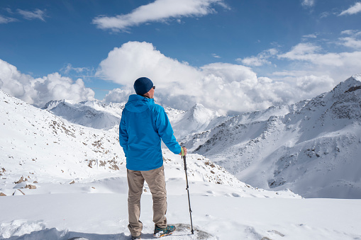 A man holding a hiking pole stands on the 4860-meter Dagu Glacier, Sichuan, China.