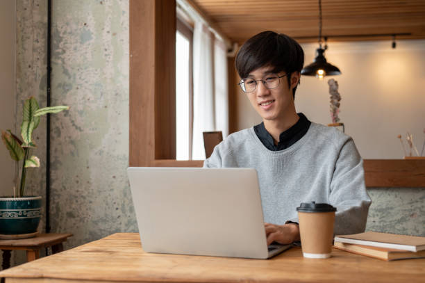 istock A happy and smart Asian male college student is using his laptop while sitting in a coffee shop. 1693081046