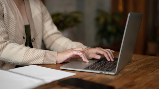 istock A woman working remotely at a coffee shop, working on her laptop, typing on keyboard. 1693081101