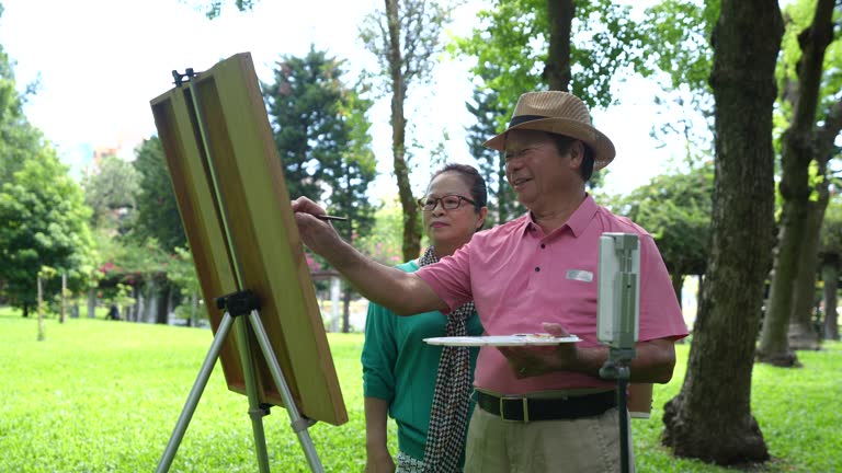 Elderly people over 60 years old paint in the park, use mobile phones to broadcast live broadcasts, and useing social media,4K video