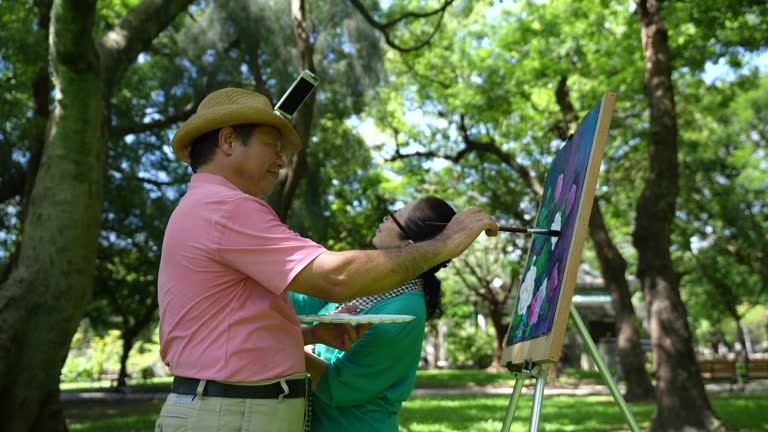 Elderly people over 60 years old paint in the park, use mobile phones to broadcast live broadcasts, and useing social media,4K video