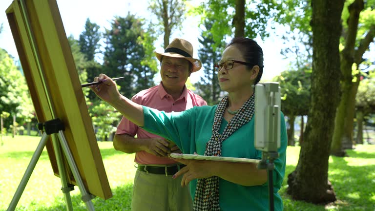 Elderly people over 60 years old paint in the park, use mobile phones to broadcast live broadcasts, and useing social media,4K video