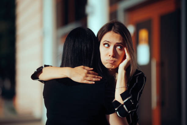 Woman Hugs Fake Friend Making Faces Behind her Back Backstabbing toxic girlfriend embracing someone with bad intentions hypocrisy stock pictures, royalty-free photos & images