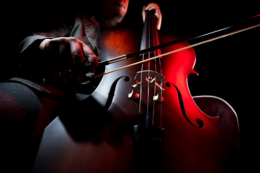 Musician playing cello. A cellist or Cello player performing with a black background