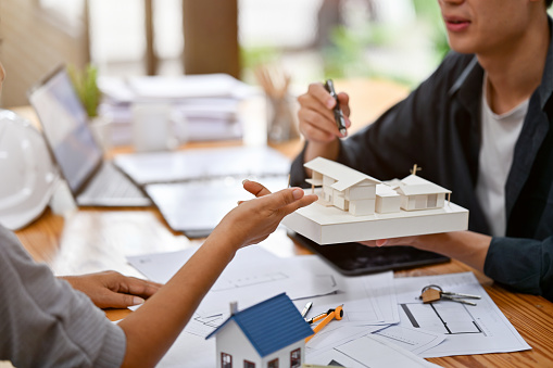 Close-up image of a female client discussing her home building design with a professional male architect or interior designer in the office.