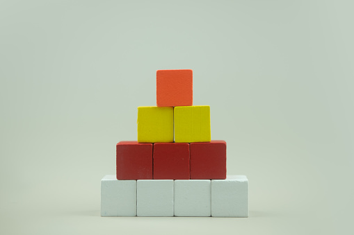 Colorful cubes wood cube arranged in pyramid shape on a white background.