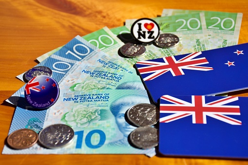 New Zealand dollars & coins money (NZD) with& tourist souvenir badges and New Zealand flags for a New Zealand travel tourism concept.