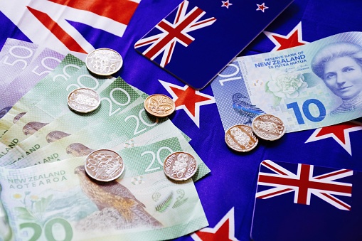 A mixture of New Zealand Bank notes and coins with New Zealand flag.