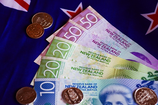A mixture of New Zealand Bank notes and coins with New Zealand flag.