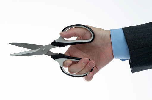 Businessman holding a pair of scissors on white background