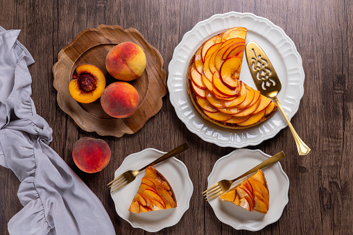 Fresh peach tart with almond cream close-up on a wooden table