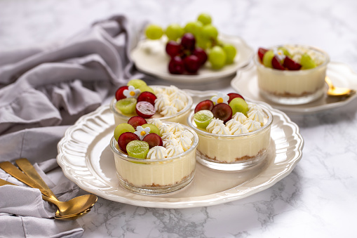 Delicious cheesecake with grapes and whipped cream on marble board