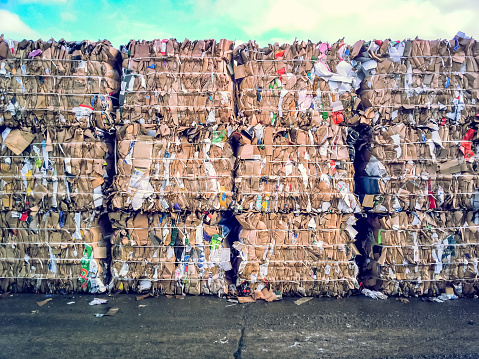 Crushed cardboard packaging ready for transport municipal waste local garbage dump recycling centre London England Europe