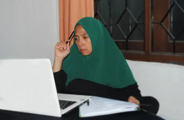 Photo of Hijab woman in expression of symbolising the suspicion caused by the manipulative nature of financial fraud.