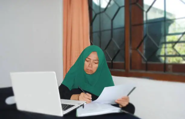 Photo of Hijab woman in expression of symbolising the suspicion caused by the manipulative nature of financial fraud.