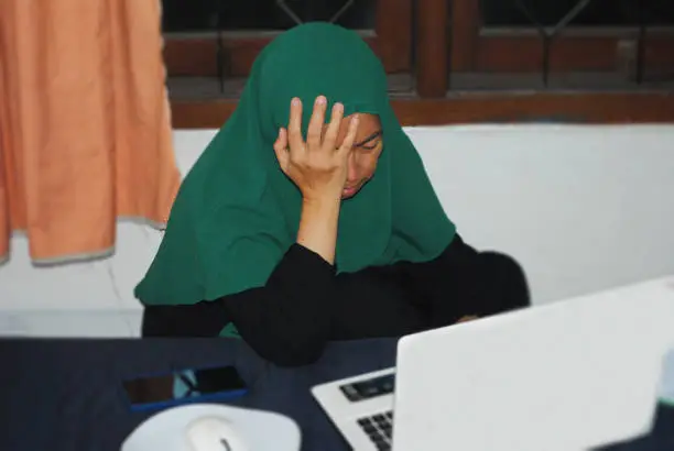 Photo of Hijab woman in expression of symbolising the suspicion caused by the manipulative nature of financial fraud.