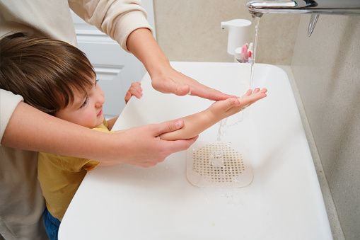 Mother and child washing their hands with soap in the bathtub. Kid aged two years (two-year-old boy)