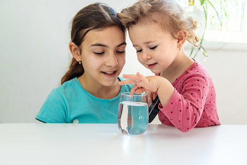 The child examines the water under a magnifying glass. Selective focus. Kid.