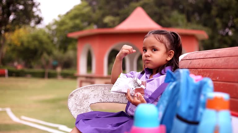 Schoolgirl enjoying snacks in park after school