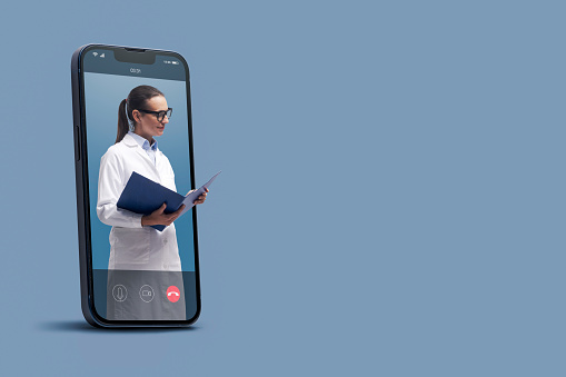 Professional doctor in a smartphone videocall and checking medical records, online doctor and telemedicine concept
