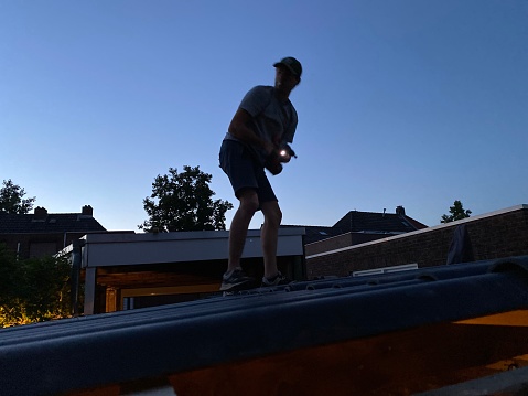 Roofer renovating a barn in the evening sun