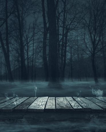 Old ruined wooden pier at the lake and moonlit misty spooky forest at night: horror background