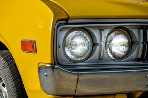 Front of classic retro car yellow,car tires and circle headlight car, headlight of a car,front light details yellow car,charm of classic retro cars.