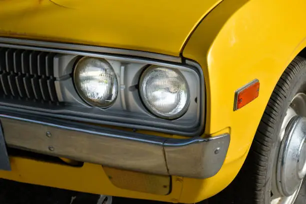 Photo of Front of classic retro car yellow,car tires and circle headlight car, headlight of a car,front light details yellow car,charm of classic retro cars.